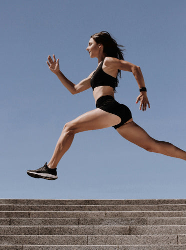 Woman running up a set of stairs against a clear blue sky